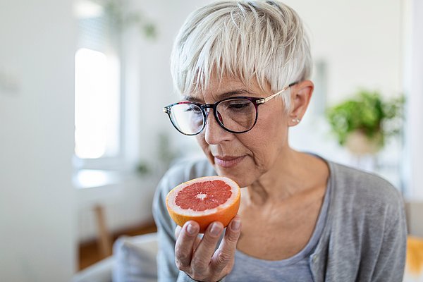 Seniorin riecht an einer Grapefruit